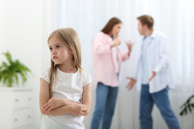 Photo of Upset little girl and her parents fighting at home, selective focus