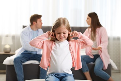 Photo of Upset little girl and her parents fighting at home, selective focus