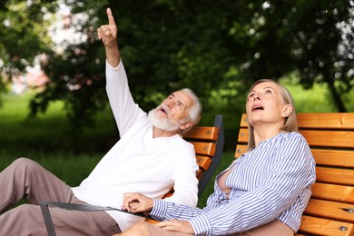 Photo of Lovely senior couple resting on wooden sunbeds in park