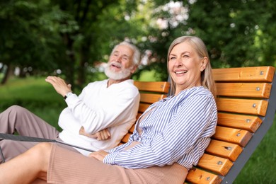 Photo of Lovely senior couple resting on wooden sunbeds in park