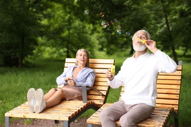 Photo of Lovely senior couple having fun with soap bubbles in park