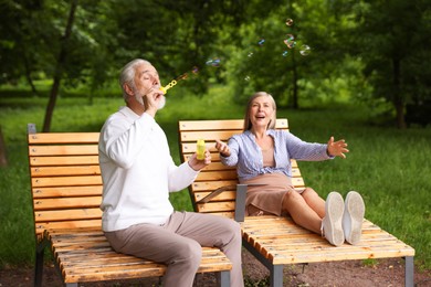 Photo of Lovely senior couple having fun with soap bubbles in park