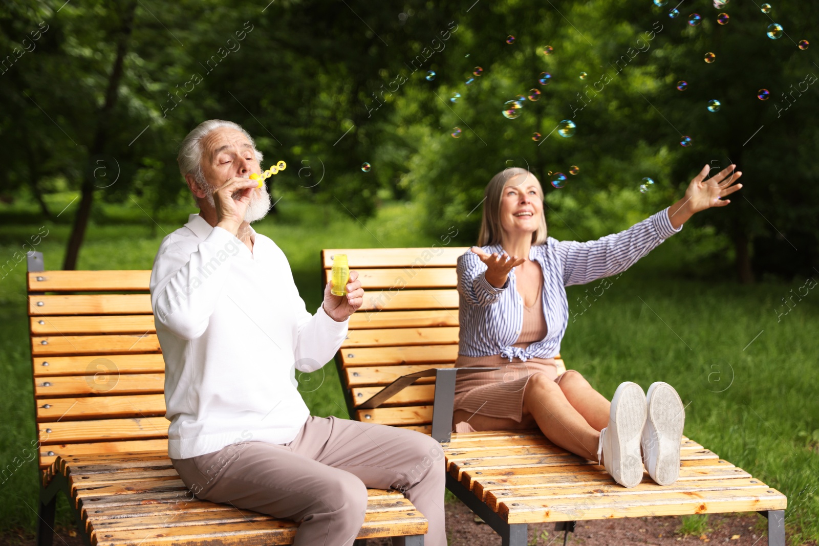 Lovely senior couple having fun with soap bubbles in park Photo of Lovely senior couple having fun with soap bubbles in park