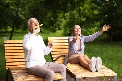 Photo of Lovely senior couple having fun with soap bubbles in park