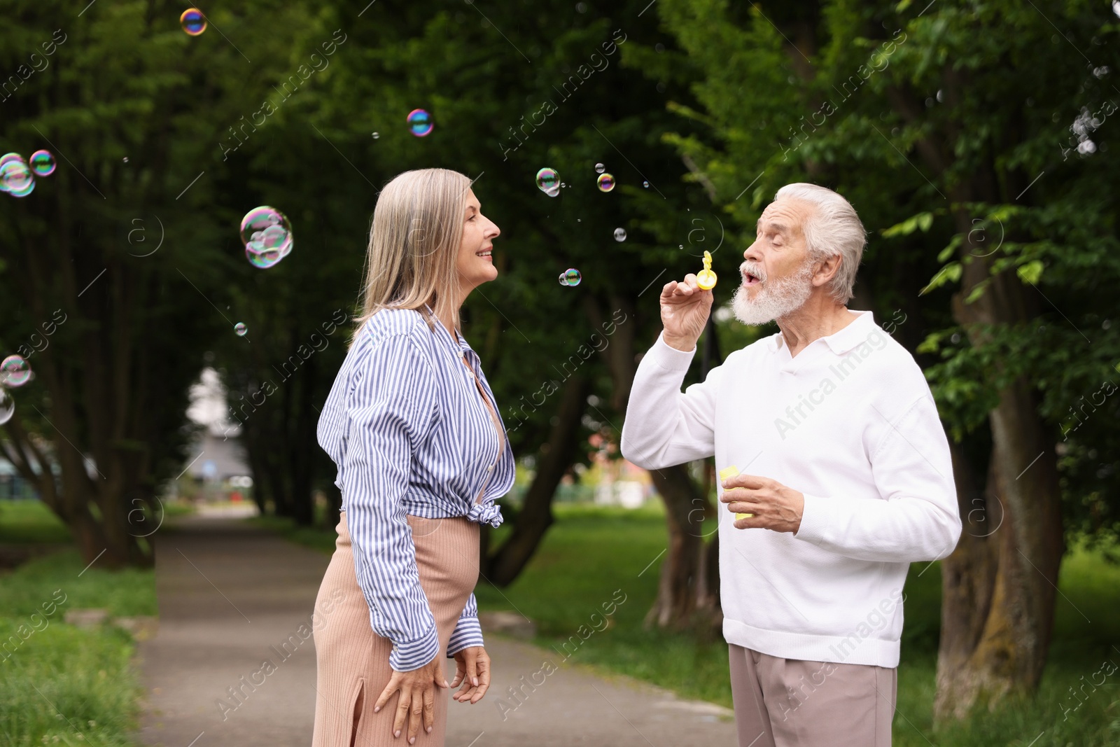 Lovely senior couple having fun with soap bubbles in park Photo of Lovely senior couple having fun with soap bubbles in park