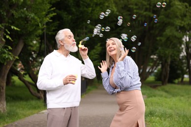 Photo of Lovely senior couple having fun with soap bubbles in park