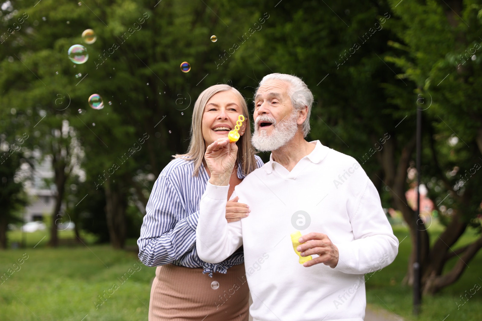 Lovely senior couple having fun with soap bubbles in park Photo of Lovely senior couple having fun with soap bubbles in park
