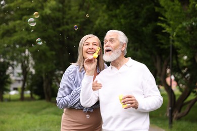 Photo of Lovely senior couple having fun with soap bubbles in park