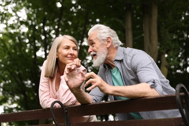 Photo of Lovely senior couple near wooden bench in park, low angle view