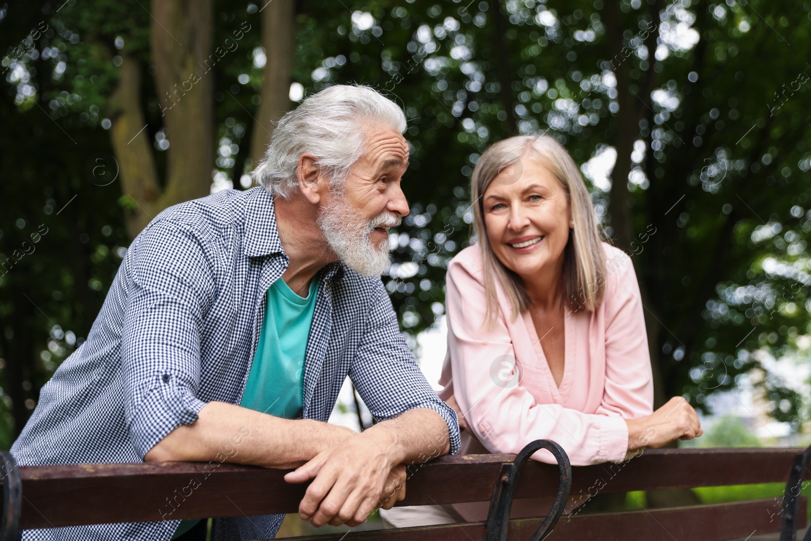 Photo of Lovely senior couple near wooden bench in park