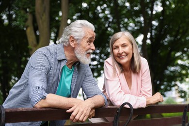 Photo of Lovely senior couple near wooden bench in park