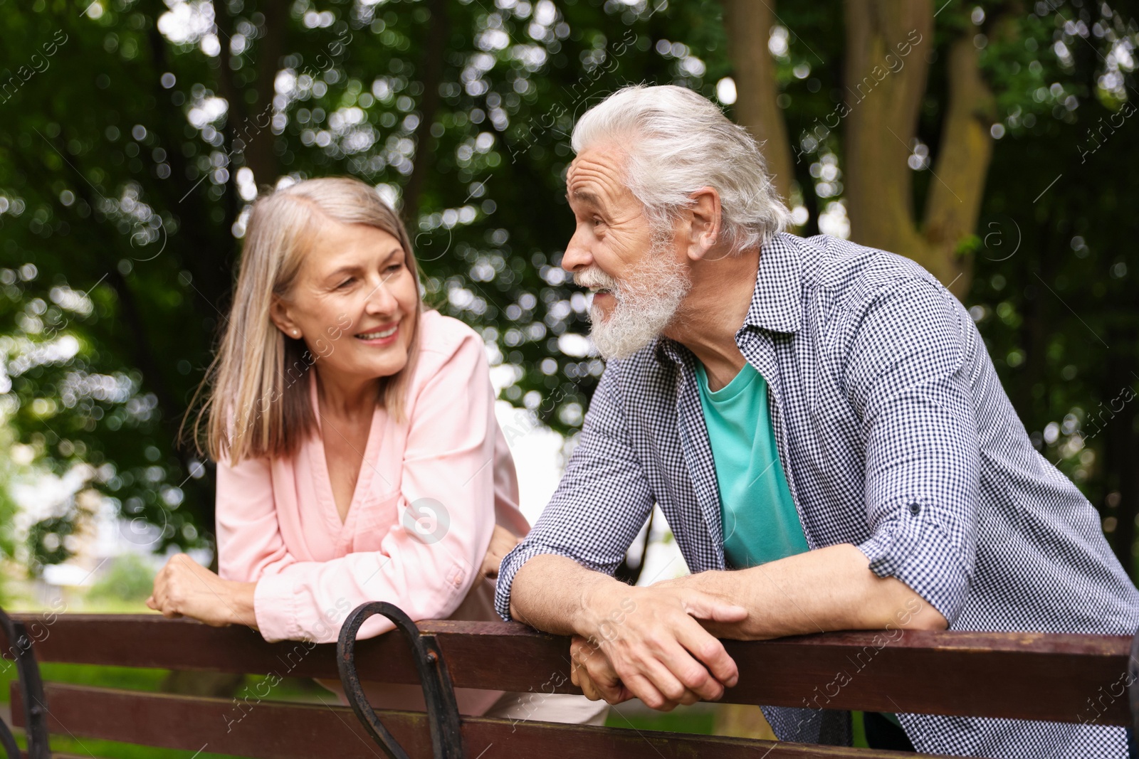 Photo of Lovely senior couple near wooden bench in park