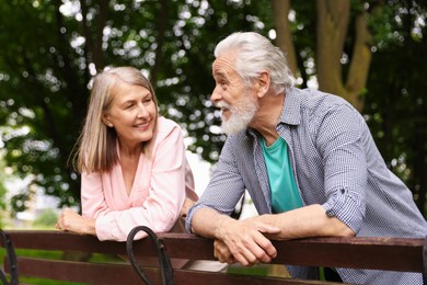 Photo of Lovely senior couple near wooden bench in park