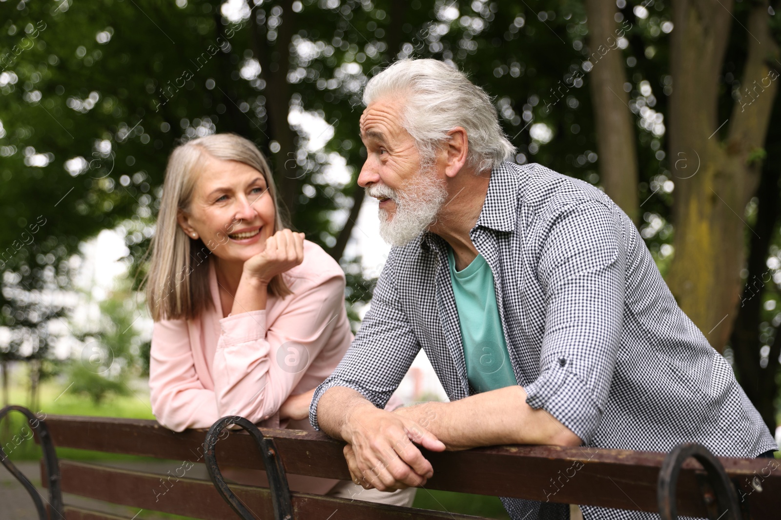 Photo of Lovely senior couple near wooden bench in park