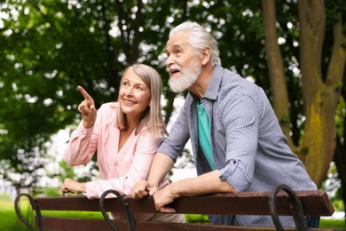 Photo of Lovely senior couple near wooden bench in park