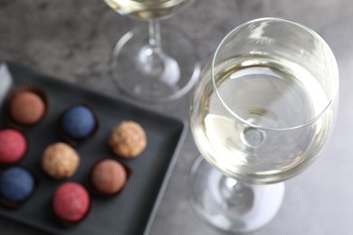 Photo of Tasty wine in glasses and truffle bonbons on grey table, above view