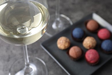 Photo of Tasty wine in glass and truffle bonbons on grey table, closeup