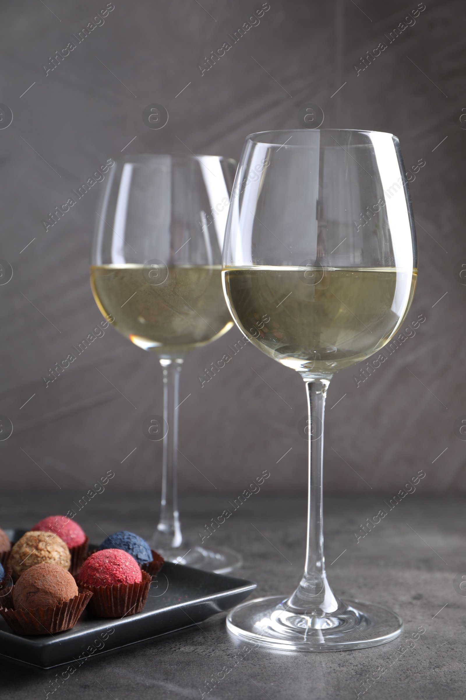Tasty wine in glasses and truffle bonbons on grey table, closeup Photo of Tasty wine in glasses and truffle bonbons on grey table, closeup