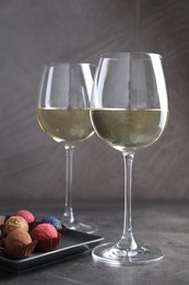 Photo of Tasty wine in glasses and truffle bonbons on grey table, closeup