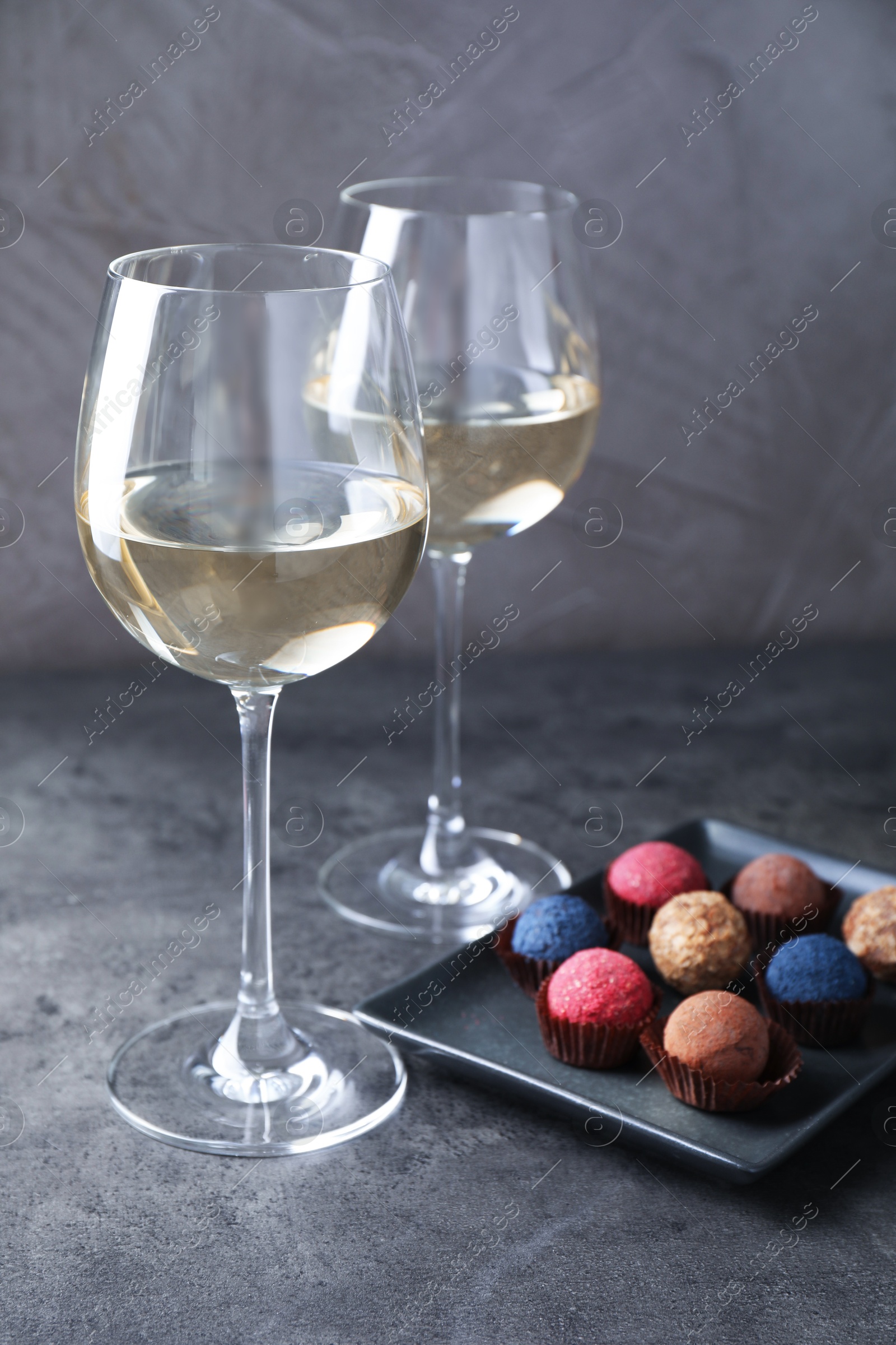 Tasty wine in glasses and truffle bonbons on grey table, closeup Photo of Tasty wine in glasses and truffle bonbons on grey table, closeup
