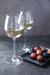 Photo of Tasty wine in glasses and truffle bonbons on grey table, closeup