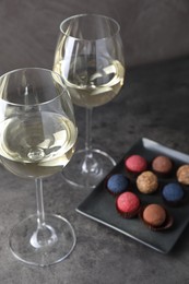 Photo of Tasty wine in glasses and truffle bonbons on grey table, closeup