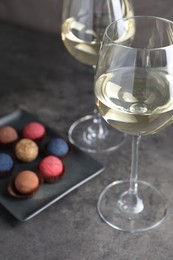 Photo of Tasty wine in glasses and truffle bonbons on grey table, closeup