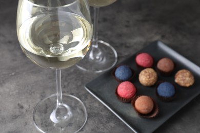 Photo of Tasty wine in glasses and truffle bonbons on grey table, closeup