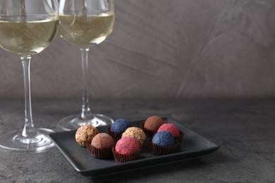 Photo of Tasty wine in glasses and truffle bonbons on grey table, closeup