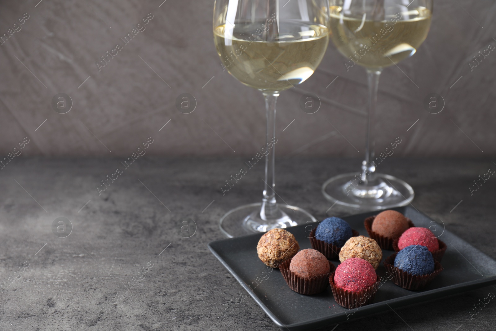 Tasty wine in glasses and truffle bonbons on grey table, closeup. Space for text Photo of Tasty wine in glasses and truffle bonbons on grey table, closeup. Space for text