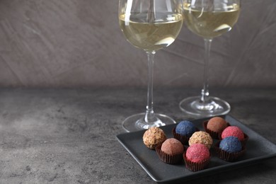 Photo of Tasty wine in glasses and truffle bonbons on grey table, closeup. Space for text