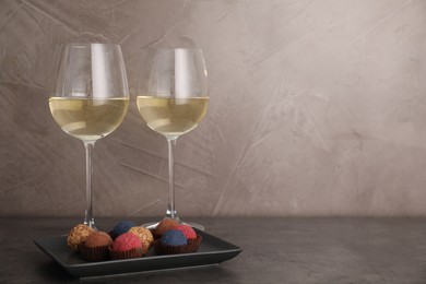 Photo of Tasty wine in glasses and truffle bonbons on grey table, space for text