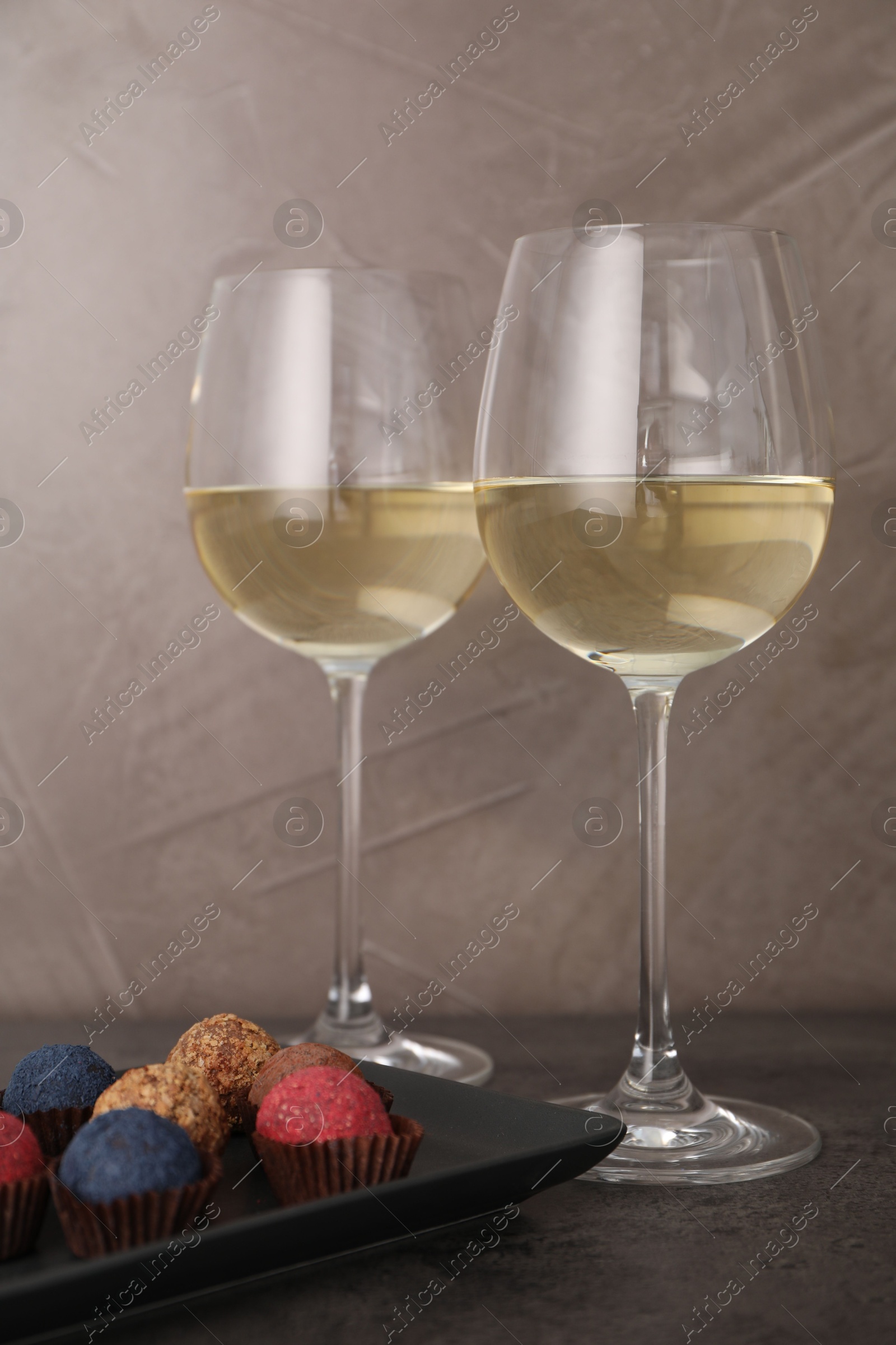 Tasty wine in glasses and truffle bonbons on grey table, closeup Photo of Tasty wine in glasses and truffle bonbons on grey table, closeup