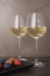 Photo of Tasty wine in glasses and truffle bonbons on grey table, closeup