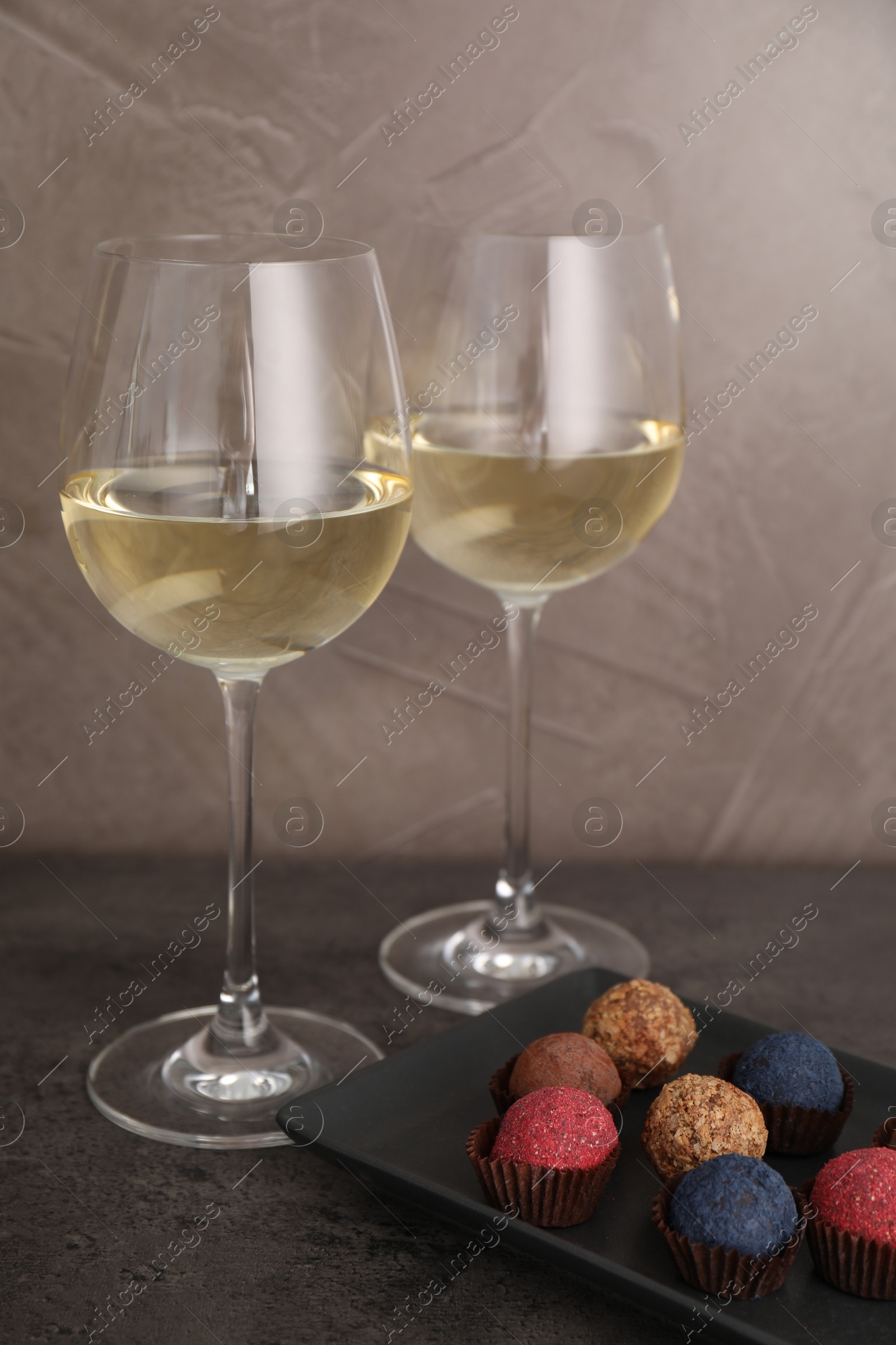 Tasty wine in glasses and truffle bonbons on grey table, closeup Photo of Tasty wine in glasses and truffle bonbons on grey table, closeup