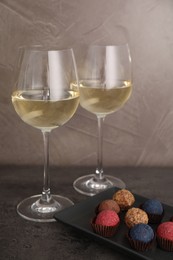 Photo of Tasty wine in glasses and truffle bonbons on grey table, closeup