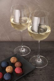 Photo of Tasty wine in glasses and truffle bonbons on grey table, closeup