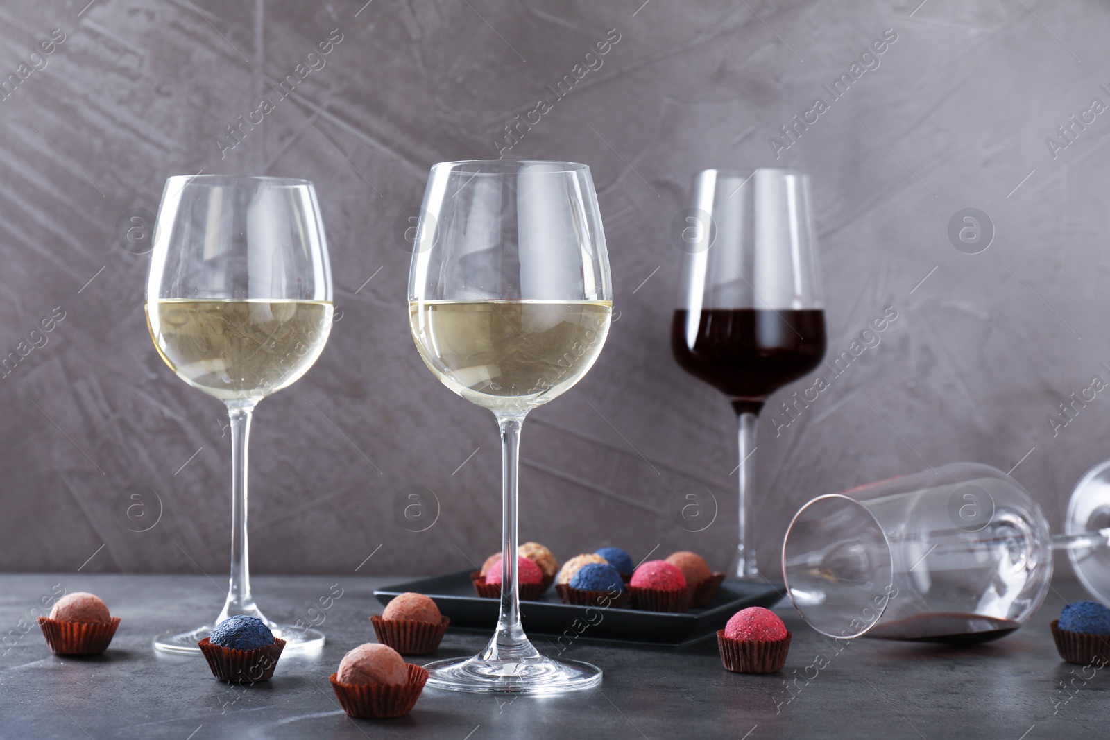 Tasty wine in glasses and truffle bonbons on grey table Photo of Tasty wine in glasses and truffle bonbons on grey table