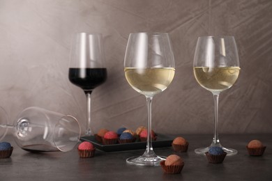 Photo of Tasty wine in glasses and truffle bonbons on grey table