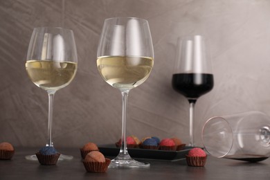 Photo of Tasty wine in glasses and truffle bonbons on grey table, low angle view