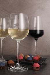 Photo of Tasty wine in glasses and truffle bonbons on grey table, closeup