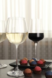 Photo of Tasty wine in glasses and truffle bonbons on grey table indoors, closeup