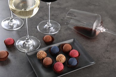 Photo of Tasty wine in glasses and truffle bonbons on grey table, above view