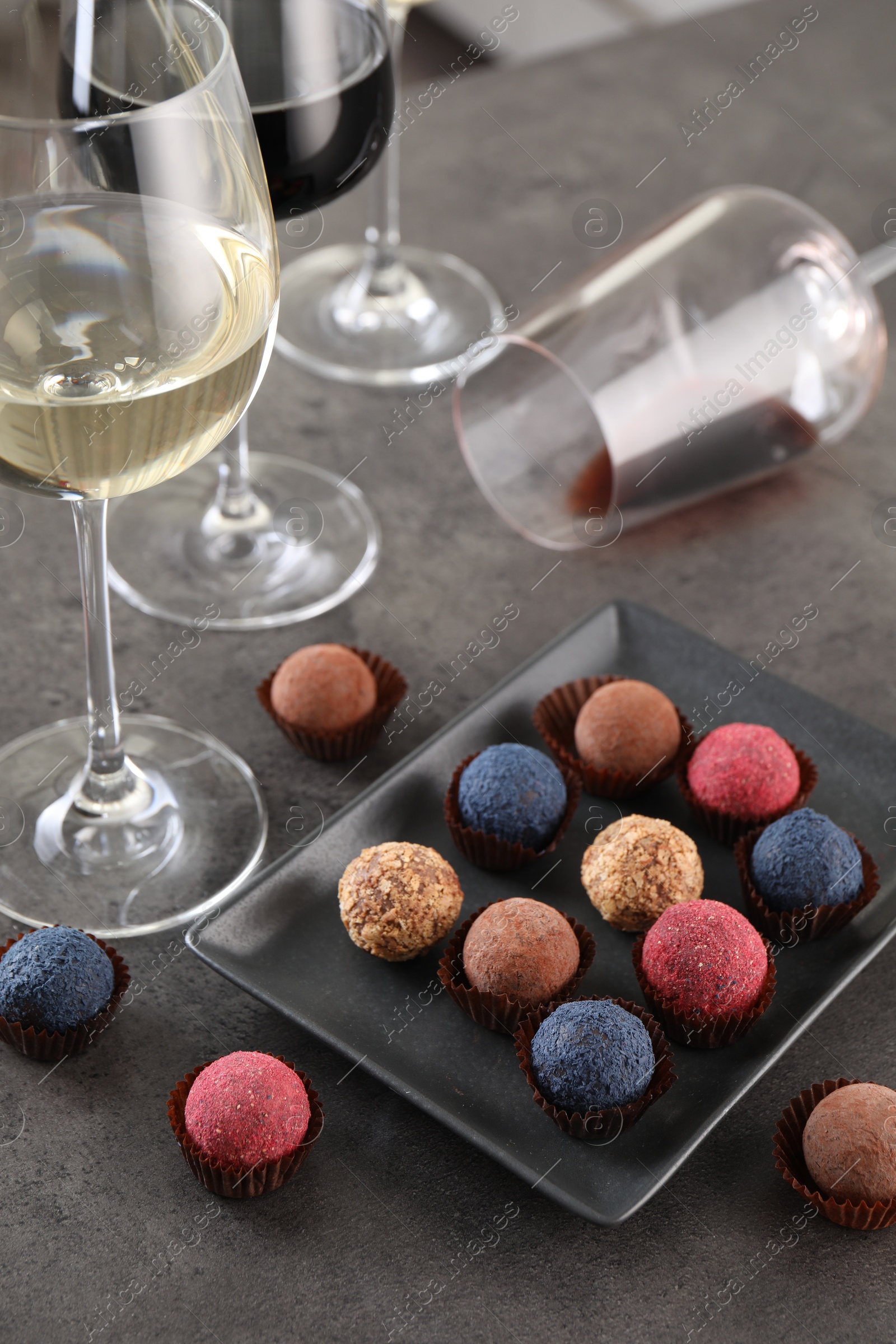 Tasty wine in glasses and truffle bonbons on grey table, above view Photo of Tasty wine in glasses and truffle bonbons on grey table, above view