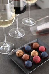 Photo of Tasty wine in glasses and truffle bonbons on grey table, closeup