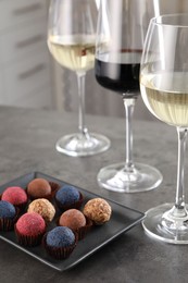 Photo of Tasty wine in glasses and truffle bonbons on grey table, closeup