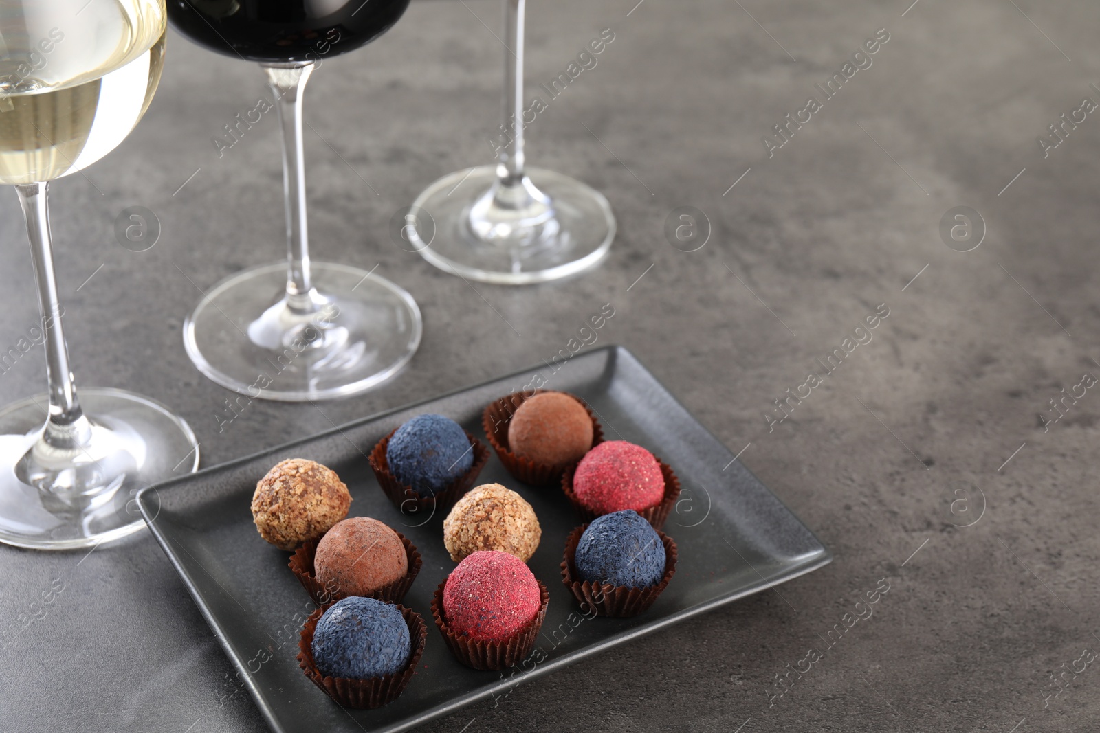 Tasty truffle bonbons and wine on grey table, above view. Space for text Photo of Tasty truffle bonbons and wine on grey table, above view. Space for text