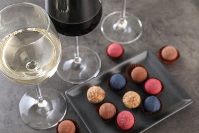 Photo of Tasty wine in glasses and truffle bonbons on grey table, above view