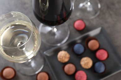 Photo of Tasty wine in glasses and truffle bonbons on grey table, above view
