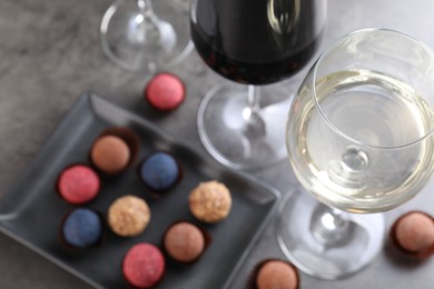 Photo of Tasty wine in glasses and truffle bonbons on grey table, above view